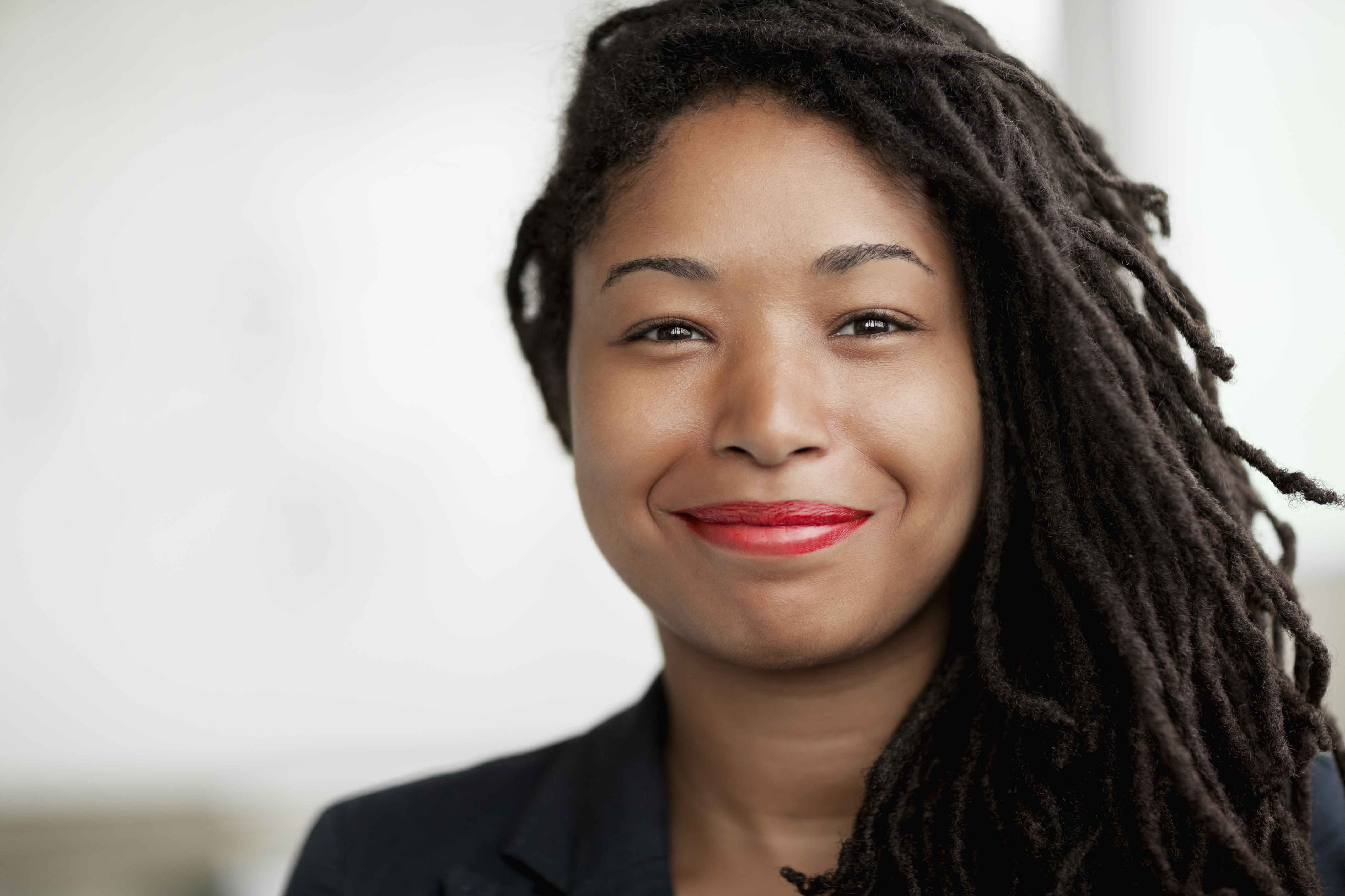 An elegantly dressed Black businesswoman wears braided hair.